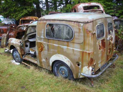 1969 MINI Cooper - This heavily rusted van sits in a junkyard, its windows broken and body showing significant decay.