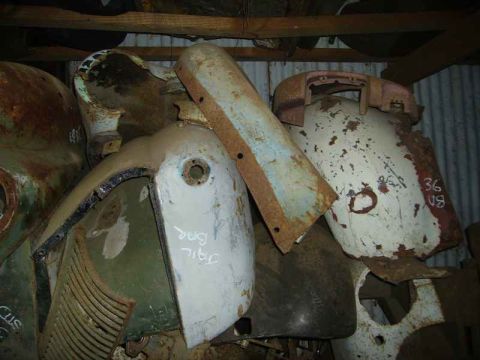 1969 MINI Cooper - Assorted vintage car body panels and parts stacked in a storage area.