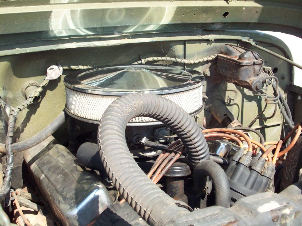 Jeep CJ5 engine bay with chrome air cleaner and orange spark plug wires.