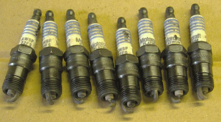 Row of eight used Motorcraft platinum spark plugs on cardboard