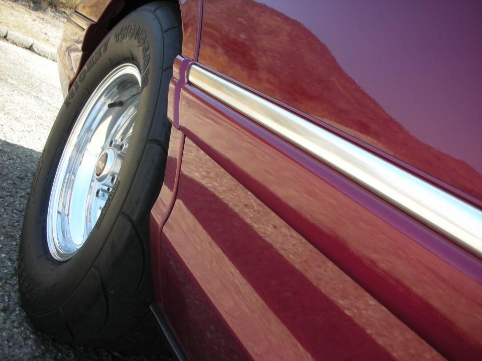 Close-up of a Mickey Thompson drag radial tire and Weld Racing wheel on a dark red vehicle.