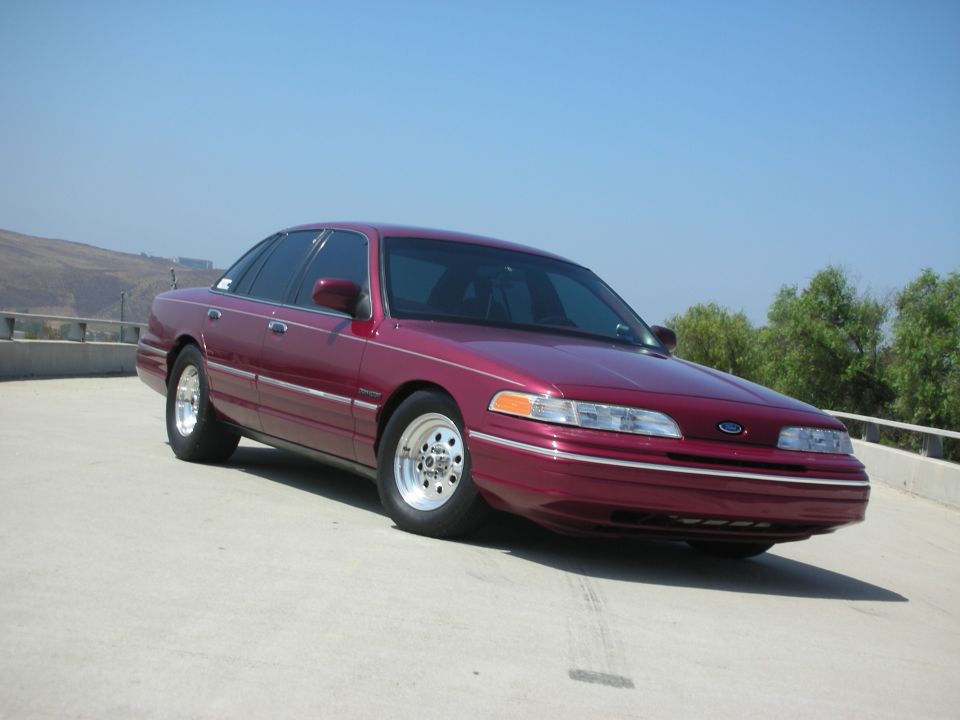 Maroon 1992 Ford Crown Victoria with chrome wheels, parked outdoors.