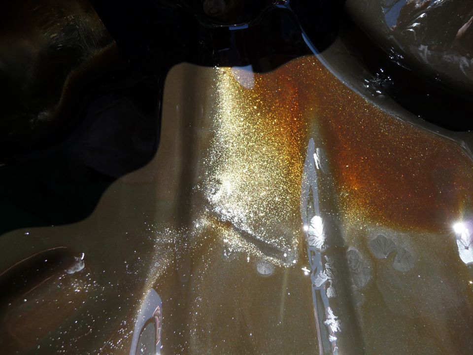 Close-up of metallic bronze car hood with shimmering glitter finish.