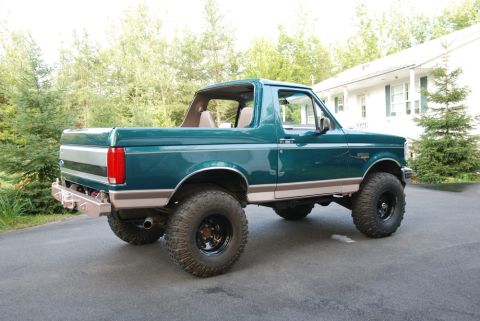 1996 Ford Bronco - Photograph of a green lifted Ford Bronco from the rear in a driveway, not a document.