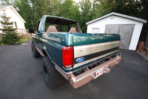 1996 Ford Bronco - Photograph of the rear of a green lifted Ford Bronco in a driveway, not a document.