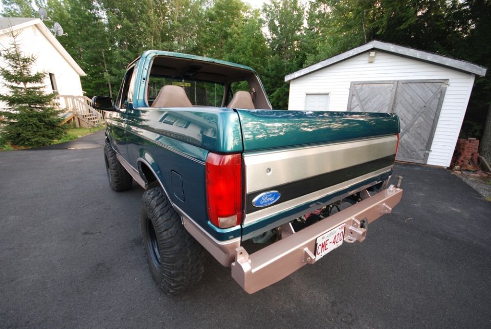 Rear photo of a green lifted Ford Bronco with tailgate and license plate