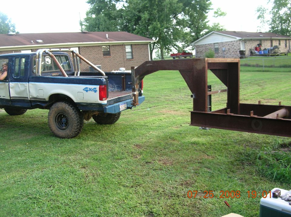 1991 Ford F-150 pickup truck with roll bar and large tires next to a rusty trailer hitch.