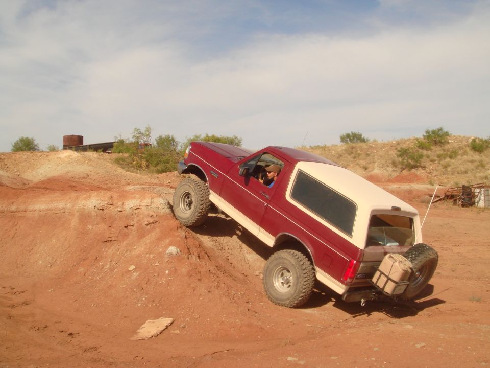 Red and cream Ford Bronco climbing a dirt hill.