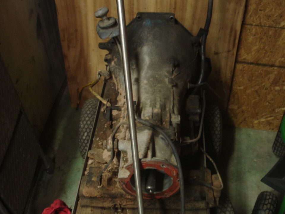 Vehicle transmission and drivetrain components on a wheeled stand.