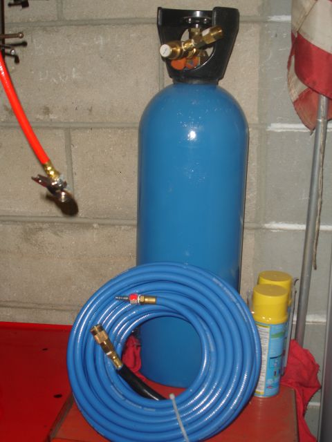 1989 Ford Bronco - Air compressor tank and hoses are set up in front of a cinder block wall.