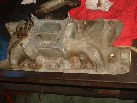 1989 Ford Bronco - Close-up of an aluminum intake manifold, likely for a V8 engine, on a work surface.