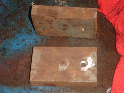 1989 Ford Bronco - Two rusty metal blocks, possibly for automotive use, are shown on a blue surface with a red cloth nearby.