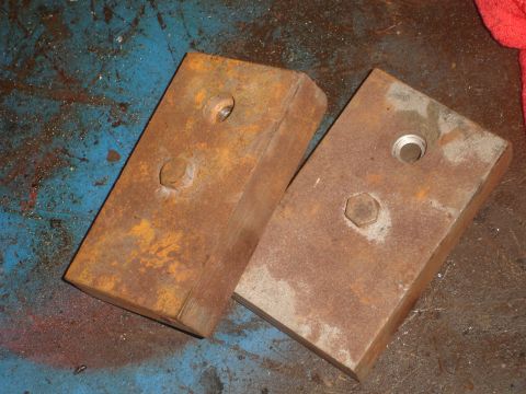 1989 Ford Bronco - Two rusty metal blocks with bolts are shown on a workshop floor.