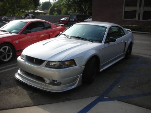 1998 Ford Crown Victoria - Photograph of a silver Ford Mustang and a red Mustang Cobra parked outdoors.