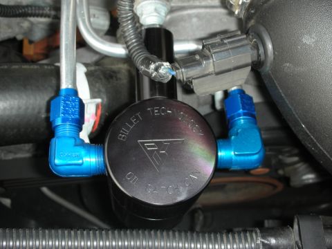 1998 Ford Crown Victoria - Close-up photograph of an installed Bullet Technology oil catch can with blue AN fittings in an engine bay.
