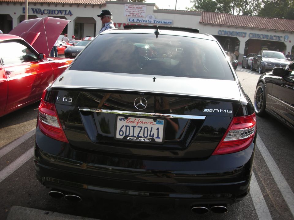 Rear view of a black Mercedes-Benz C63 AMG sedan at a car meet