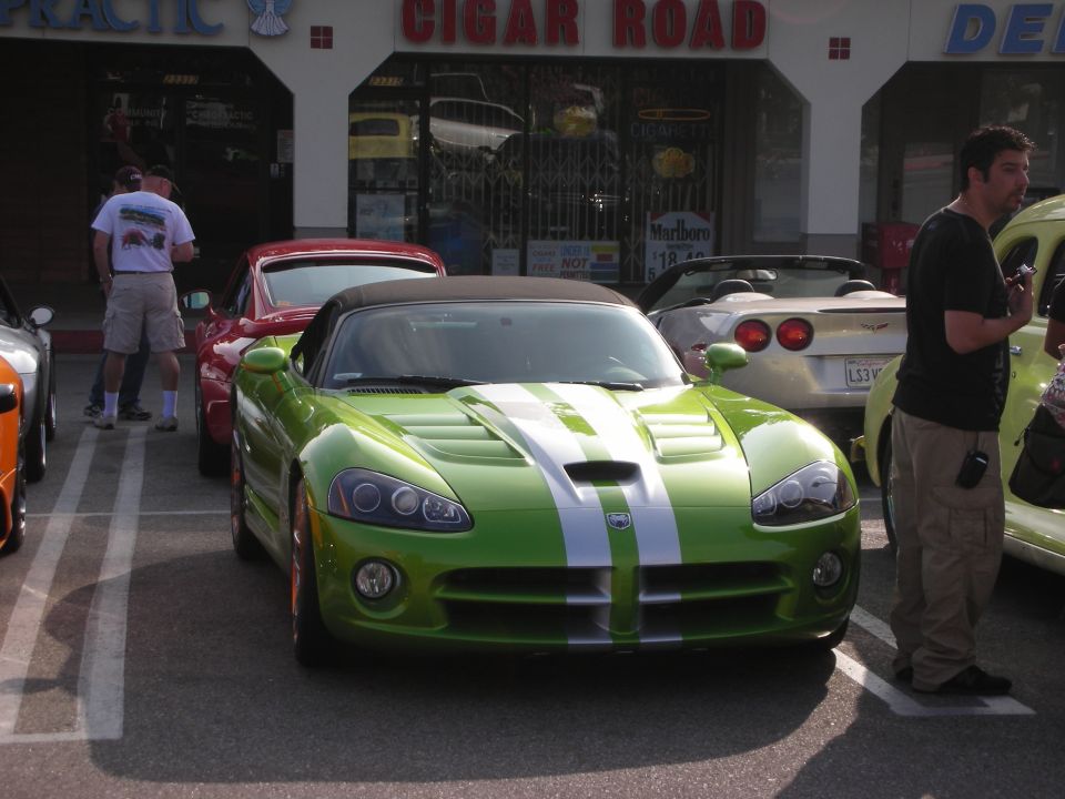 Green Dodge Viper with white racing stripes at a car show