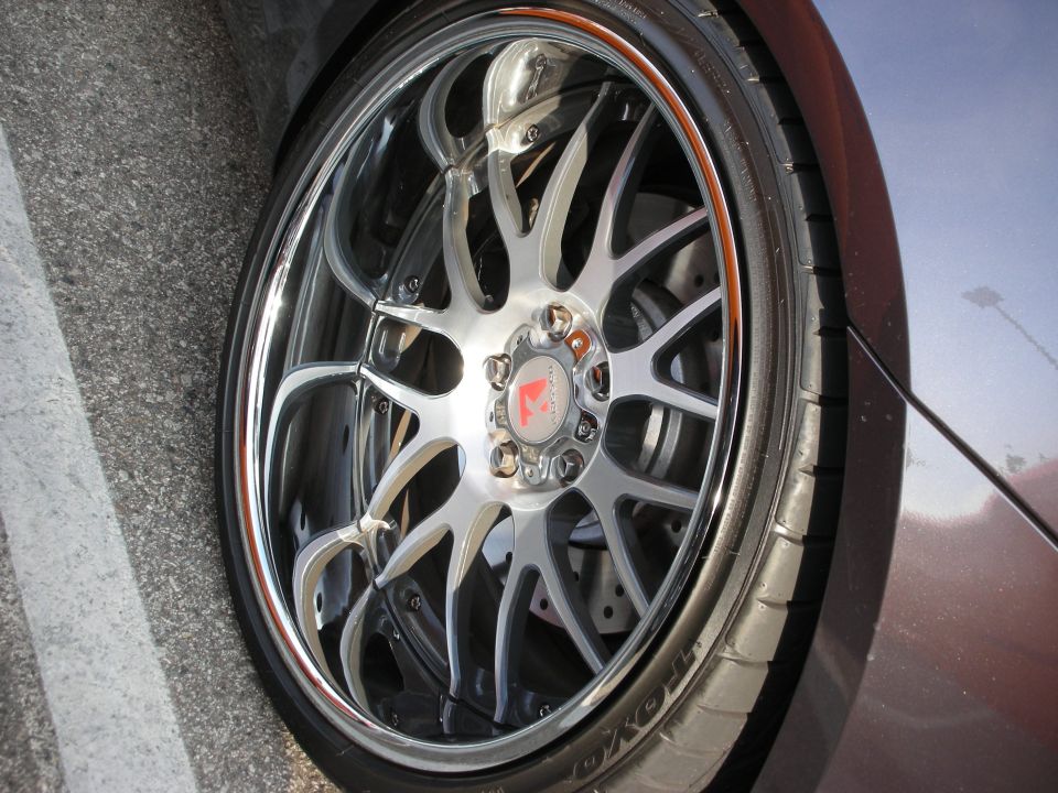 Close-up of a chrome mesh-style alloy wheel and tire on a dark coupe
