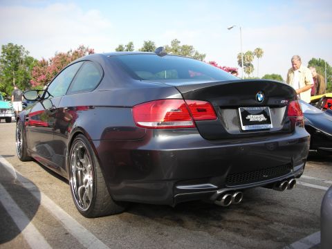 1998 Ford Crown Victoria - Photograph of a dark gray BMW M3 coupe from the rear at an outdoor car meet, not a technical document.