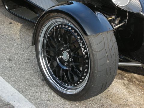 1998 Ford Crown Victoria - Close-up of a black multi-spoke wheel with polished lip and low-profile tire on a dark-bodied vehicle.