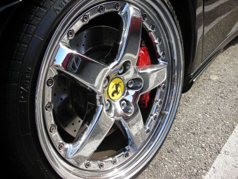1998 Ford Crown Victoria - Photograph of a Ferrari's polished five-spoke alloy wheel and red brake caliper, not a technical document.