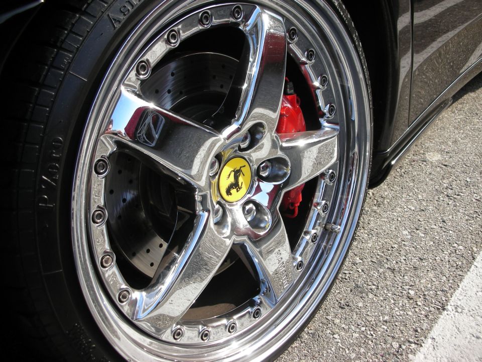 Close-up of a chrome five-spoke Ferrari alloy wheel with red brake caliper