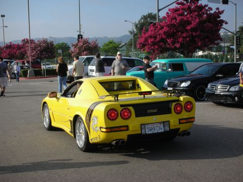 1998 Ford Crown Victoria - Photograph of a yellow custom mid-engine sports car from the rear at a car meet, not a technical document.