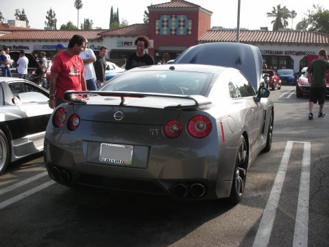 1998 Ford Crown Victoria - Photograph of a gray Nissan GT-R from the rear at an outdoor car meet, not a technical document.