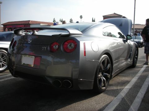 1998 Ford Crown Victoria - Photograph of a gray Nissan GT-R from the rear quarter at an outdoor car meet, not a technical document.