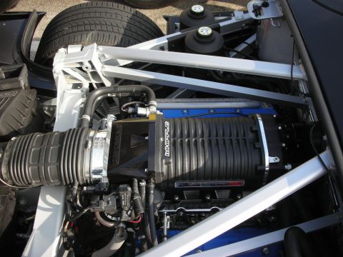 1998 Ford Crown Victoria - Photograph of a supercharged engine in the rear bay of a black supercar, not a technical document.