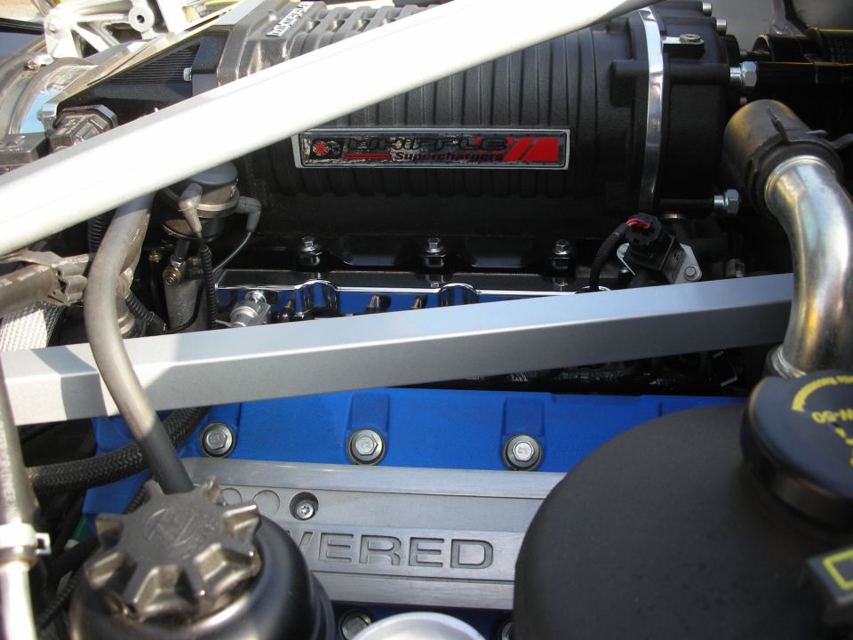 Close-up of a supercharger and engine cover inside a car engine bay