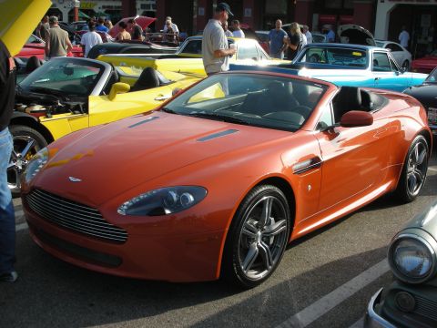 1998 Ford Crown Victoria - Photograph of an orange Aston Martin V8 Vantage roadster at an outdoor car meet, not a technical document.