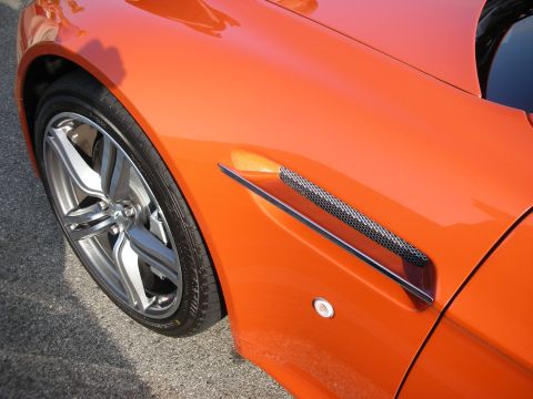 1998 Ford Crown Victoria - Photograph of an orange sports car's front fender, wheel and side vent, not a technical document.