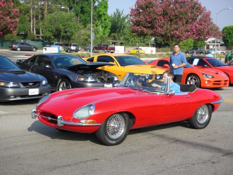 1998 Ford Crown Victoria - Photograph of a red Jaguar E-Type roadster among other cars at a car meet, not a technical document.