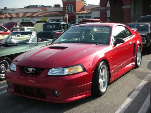 1998 Ford Crown Victoria - Photograph of a red Roush-modified Ford Mustang coupe at an outdoor car show, not a technical document.