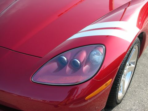 1998 Ford Crown Victoria - Photograph of the front fender, headlight and stripe of a red Corvette, not a technical document.