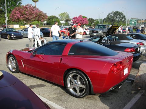 1998 Ford Crown Victoria - Photograph of a red C6 Corvette coupe in a parking lot at a car meet, not a technical document.