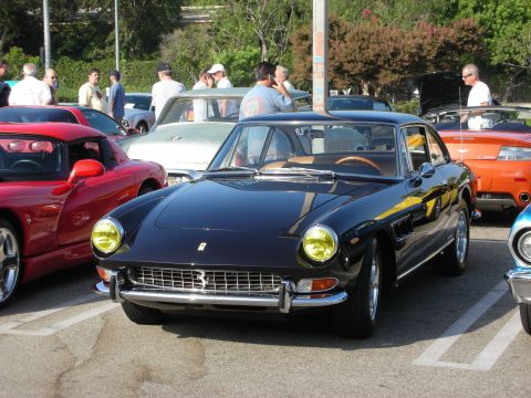 1998 Ford Crown Victoria - Front three-quarter of a black classic Ferrari coupe with yellow headlights among other cars.