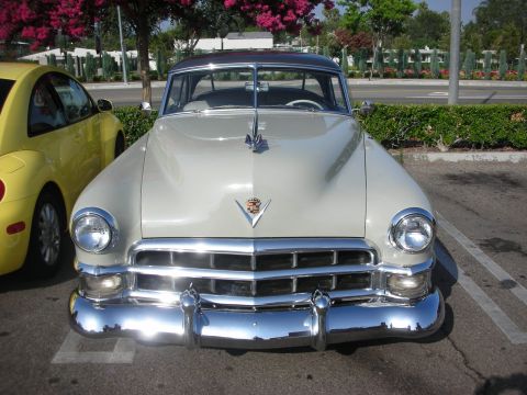 1998 Ford Crown Victoria - Front view of a cream 1949 Cadillac convertible with chrome bumper and V crest emblem.