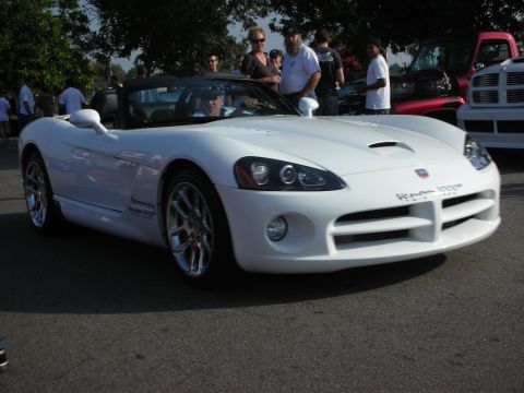 1998 Ford Crown Victoria - Front three-quarter of a white Dodge Viper convertible with spectators in the background.