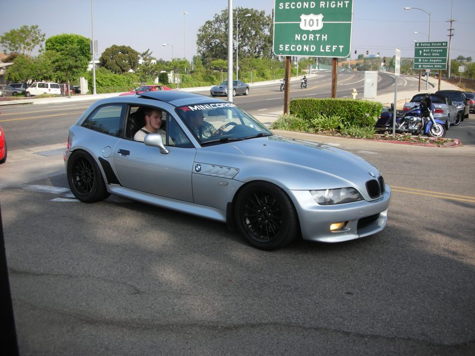 Silver BMW Z3 coupe being driven on a street near a highway sign