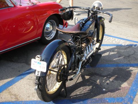 1998 Ford Crown Victoria - Rear view of a vintage black motorcycle next to a red Porsche 356 at an outdoor car show.