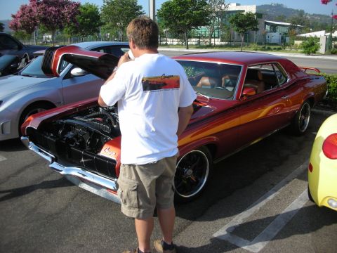 1998 Ford Crown Victoria - Photograph of a custom orange Mercury at a car show with its hood open, not a technical document.