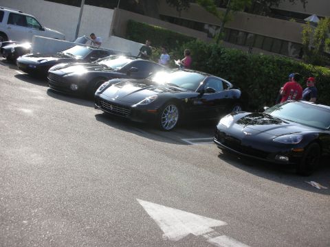 1998 Ford Crown Victoria - Photograph of a row of modern black sports cars at an outdoor car gathering, not a technical document.
