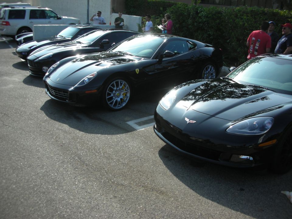 Several dark-colored cars parked in a row, side view