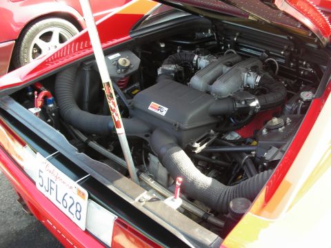 1998 Ford Crown Victoria - The engine bay of a red car is open, revealing its components and a K&N air filter.