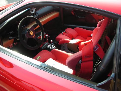 1998 Ford Crown Victoria - The interior of a red car shows racing seats and a Ferrari emblem on the steering wheel.