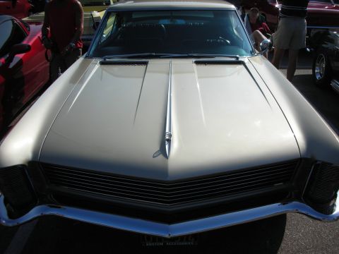 1998 Ford Crown Victoria - Photograph of the front hood and grille of a gold vintage Buick Riviera, not a technical document.