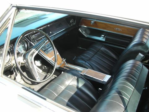 1998 Ford Crown Victoria - Photograph of a vintage Buick Riviera interior with black seats and woodgrain trim, not a technical document.