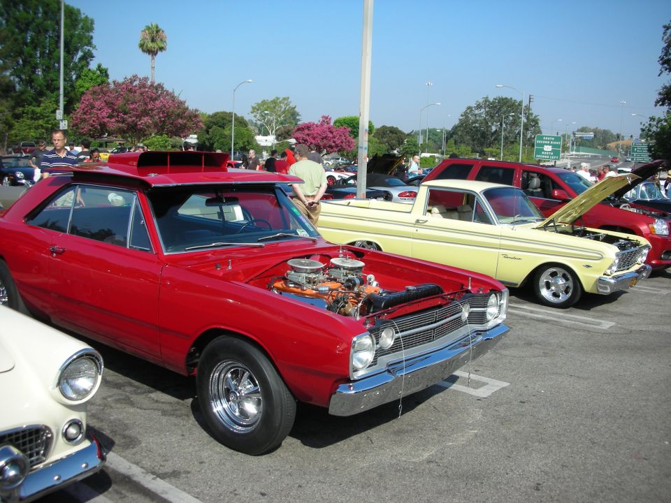 Red Dodge Dart with hood open showing engine at a car show